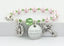 Pink pearl and green crystal rosary bracelet with an engraved disc and charms.