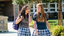 Two teenage girls walking and smiling on a school campus. 