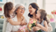 Grandma, daughter, and 2 granddaughters smiling holding flowers and custom mother's day rosary gift.