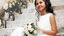 First Communion girl sitting on step with flowers.