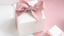 White box with a pink bow on a pink and white bakground.