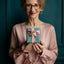 Woman in front of a green wall holding a green and pink wrapped present. 