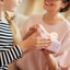 Mother and daughter looking at each other and smiling while daughter holds a lavender wrapped present. 