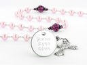 Pink rosary with purple crystals and an engraved disc. 
