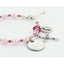 Pink pearl and crystal rosary bracelet with an engraved disc and charms.