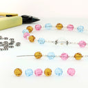 Multi-colored birthstone crystals with silver daisies and a beading tool. 