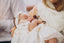 Mother holding baby in a white baptism gown. 